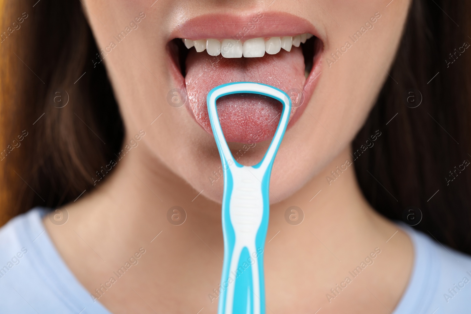 Photo of Woman brushing her tongue with cleaner, closeup