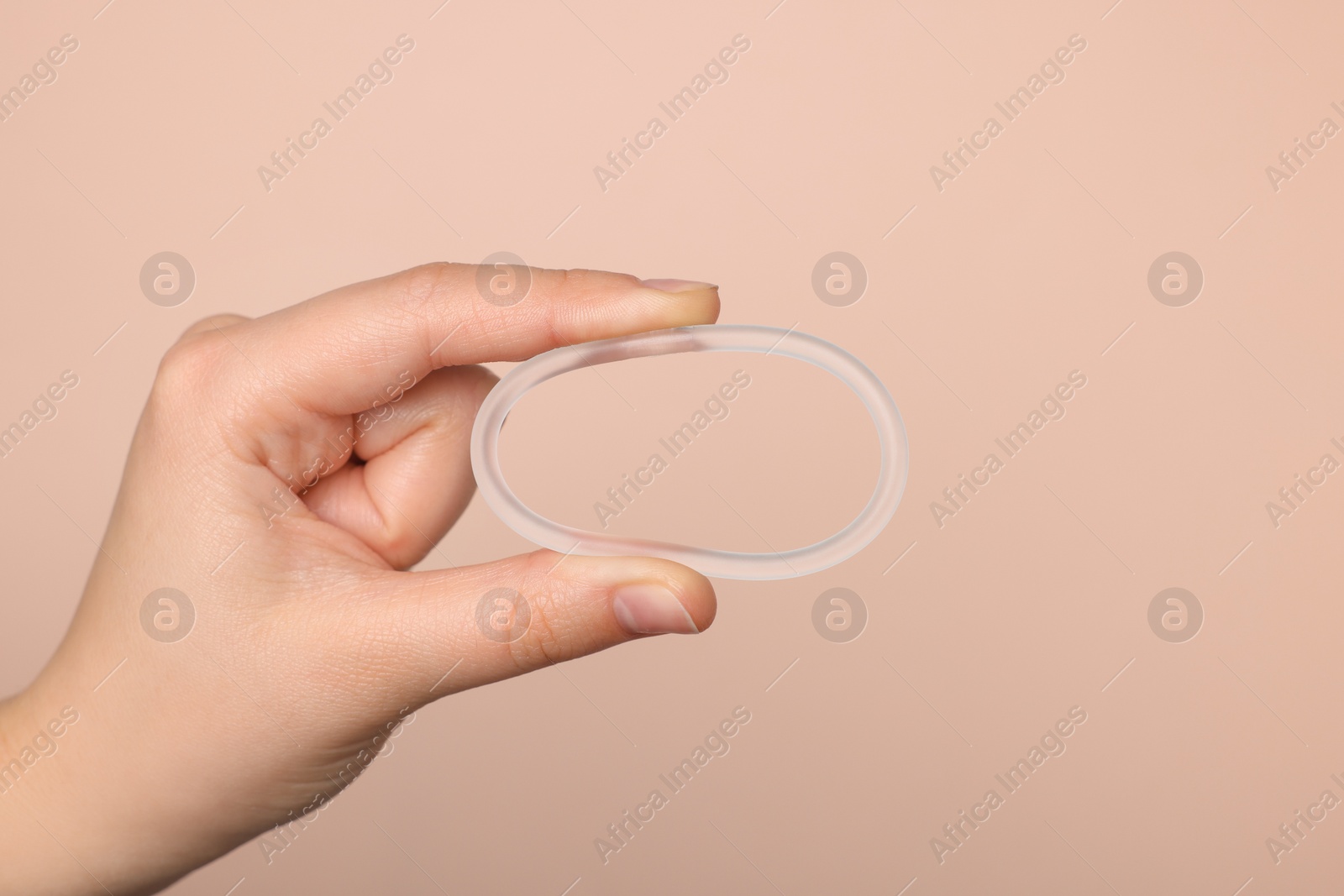 Photo of Woman holding diaphragm vaginal contraceptive ring on beige background, closeup. Space for text