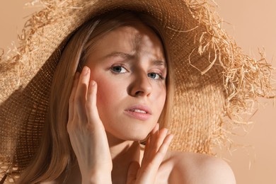 Beautiful young woman in straw hat on beige background, closeup
