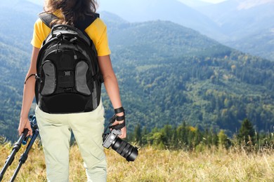 Photo of Photographer with backpack, camera and tripod surrounded by breathtakingly beautiful nature