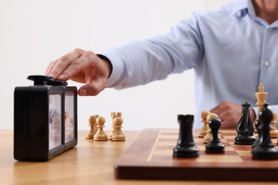 Photo of Man turning on chess clock during tournament at table, closeup