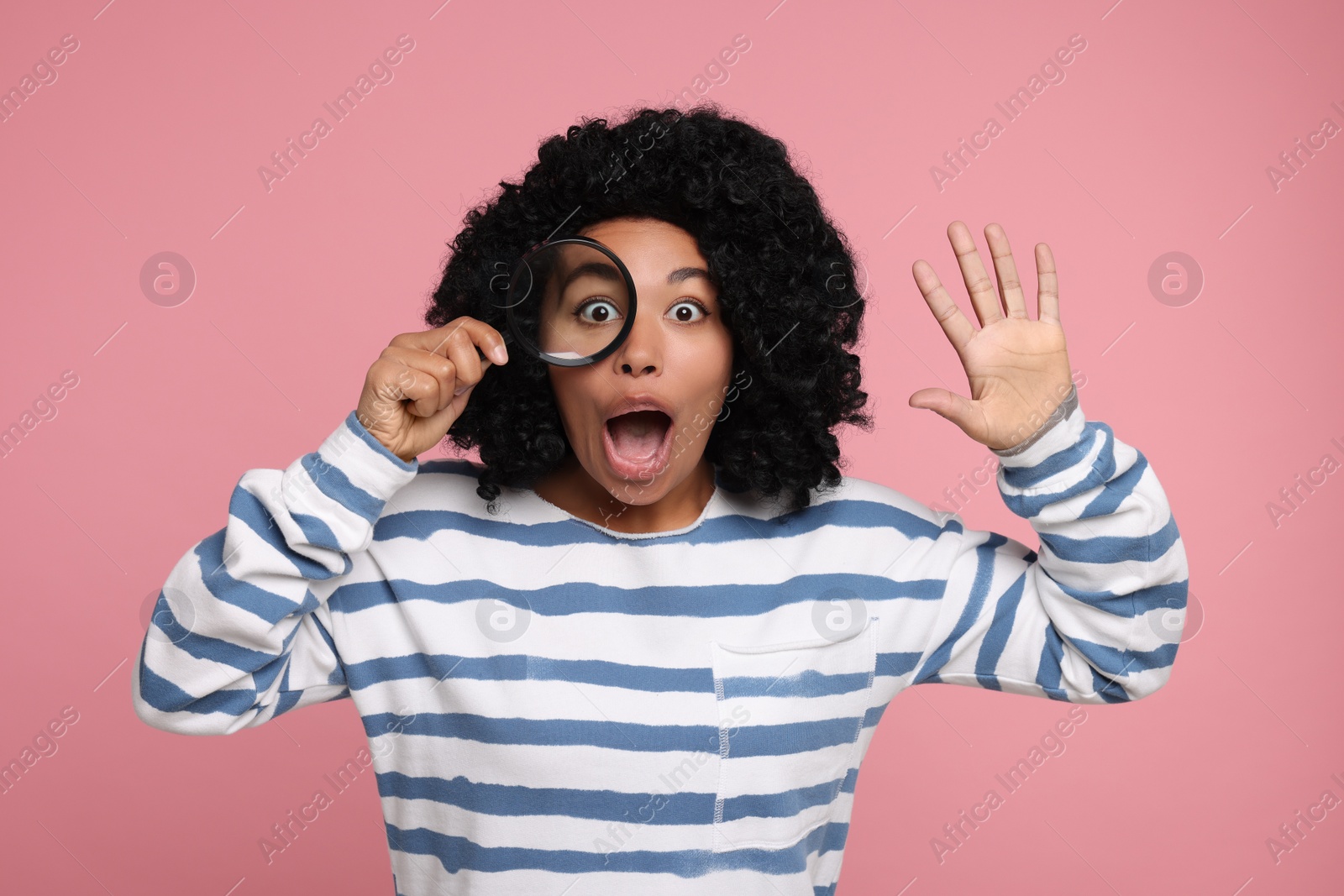 Photo of Emotional woman looking through magnifier glass on pink background