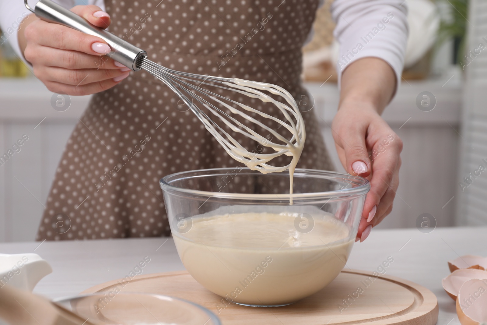 Photo of Woman making dough with whisk in bowl at table, closeup