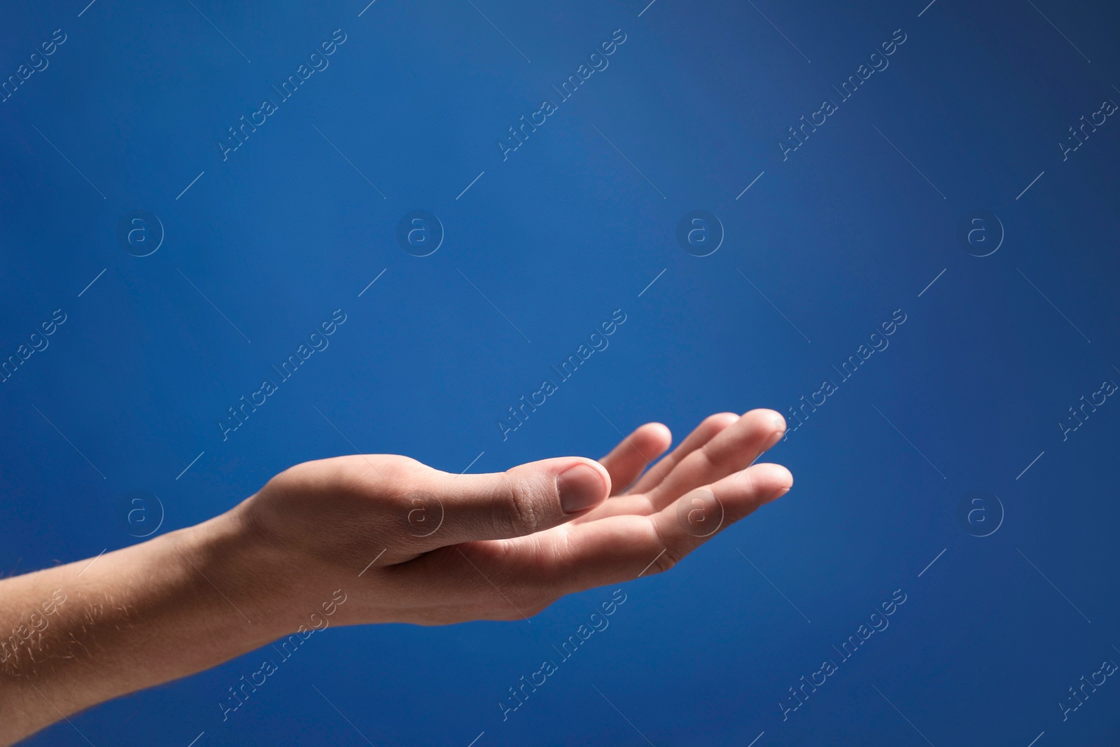 Photo of Man holding something in hand on blue background, closeup. Space for text
