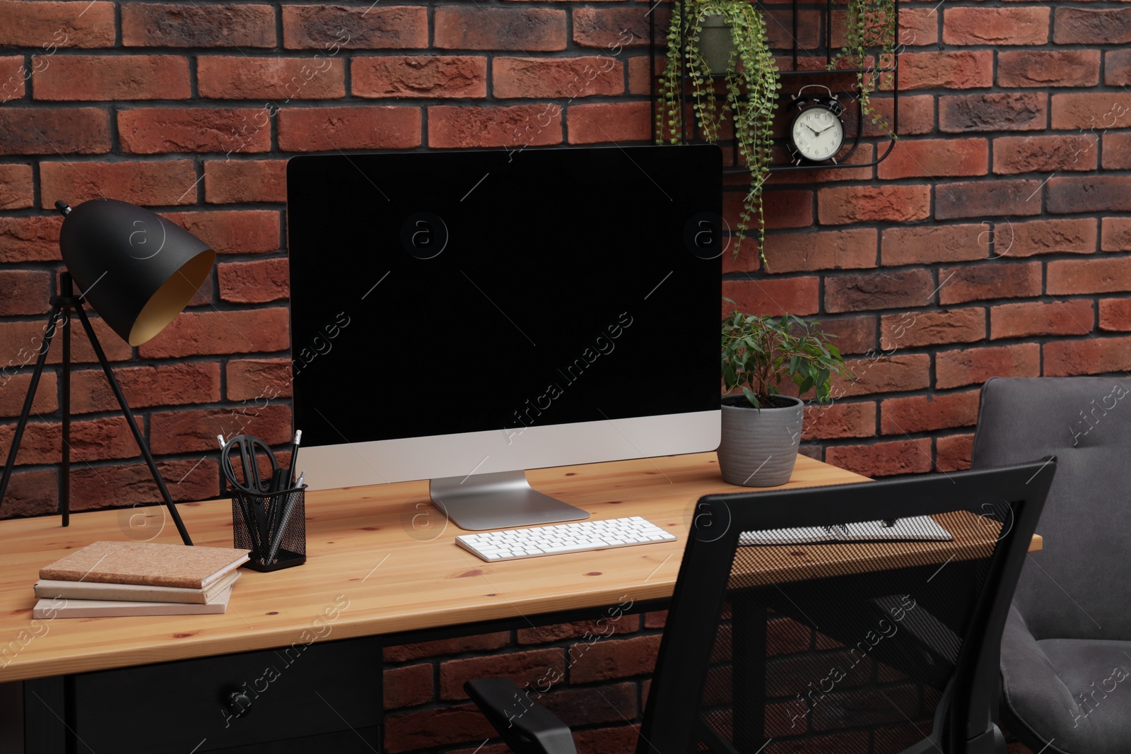 Photo of Cozy workplace with modern computer on desk and comfortable chair at home