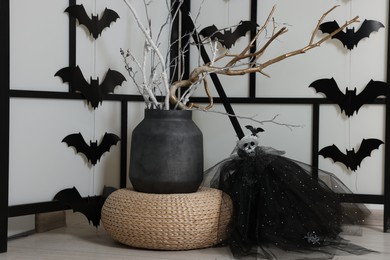 Paper bats and festive decor near white wall. Halloween celebration