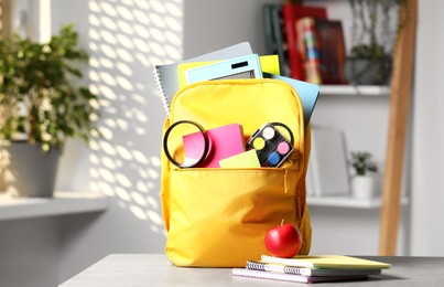 Photo of Yellow backpack and different school stationery on table indoors