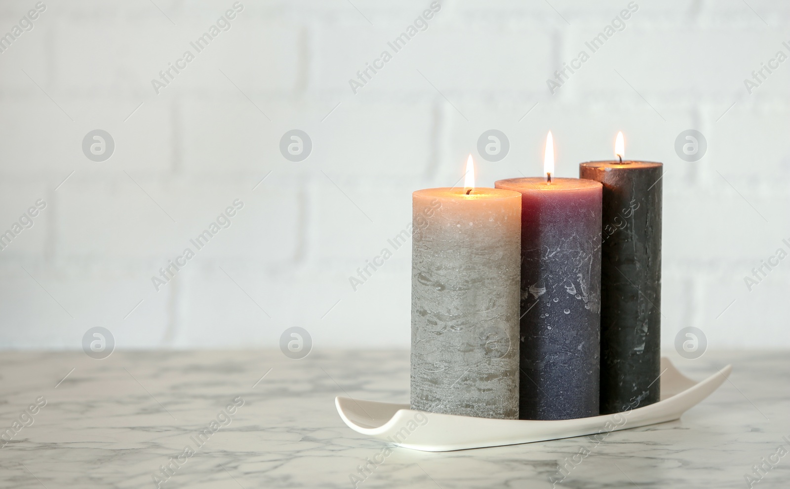 Photo of Decorative wax candles on table against brick wall