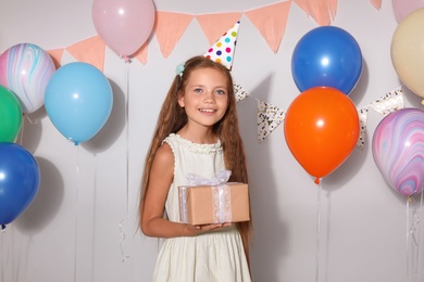 Photo of Happy girl with gift box at birthday party indoors