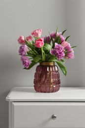 Photo of Beautiful bouquet of colorful tulip flowers on white bedside table indoors