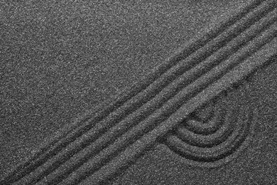 Photo of Pattern on decorative black sand, top view. Zen and harmony