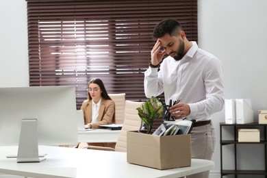 Photo of Dismissed man packing personal stuff into box in office