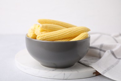 Photo of Tasty fresh yellow baby corns in bowl on white table