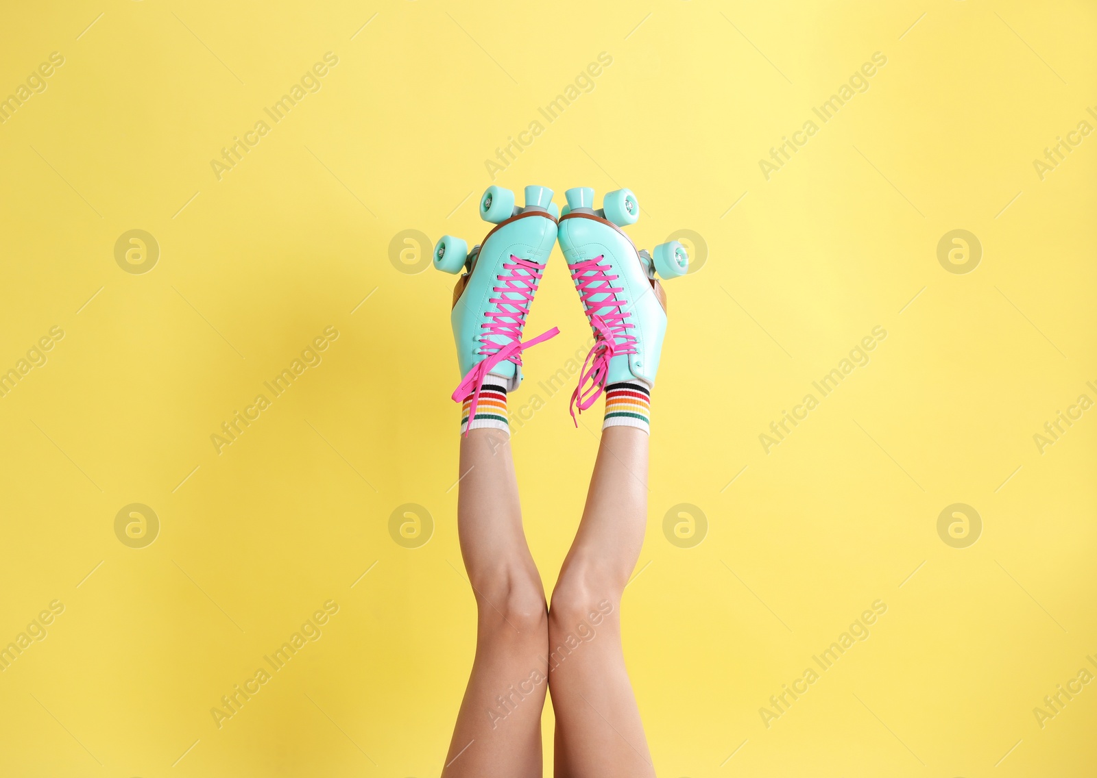 Photo of Young woman with retro roller skates on color background, closeup