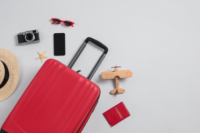 Flat lay composition with suitcase and travel accessories on grey background, space for text. Summer vacation