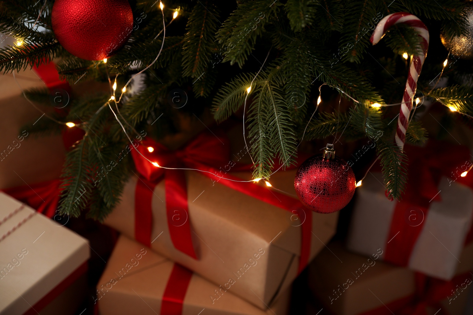 Photo of Beautiful decorated Christmas tree with fairy lights and gift boxes, closeup