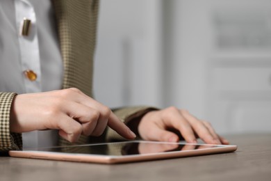Photo of Closeup view of woman using new tablet at table on blurred background. Space for text