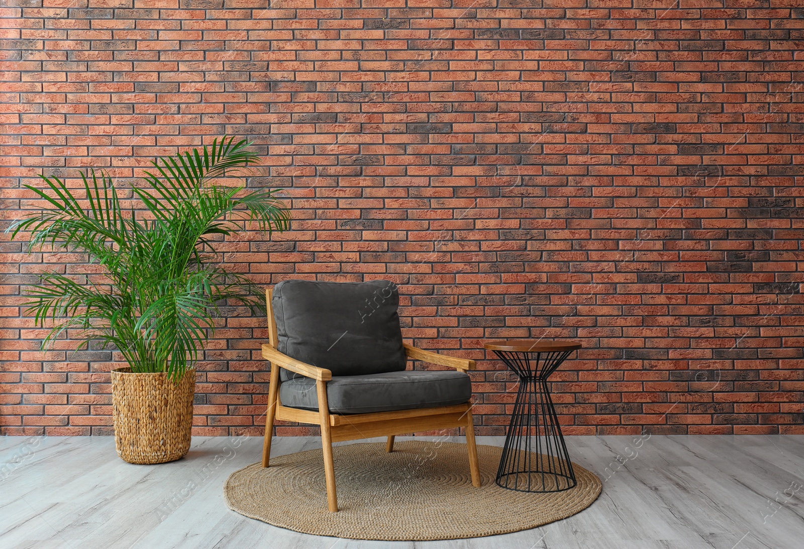 Photo of Modern room interior with stylish grey armchair and potted plant near brick wall