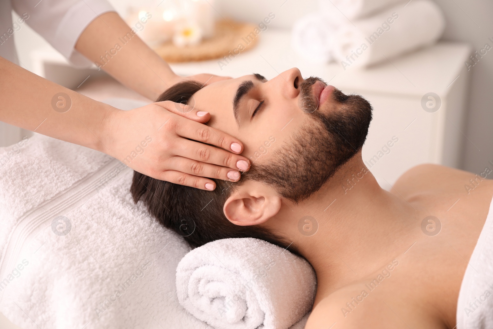 Photo of Young man receiving facial massage in beauty salon