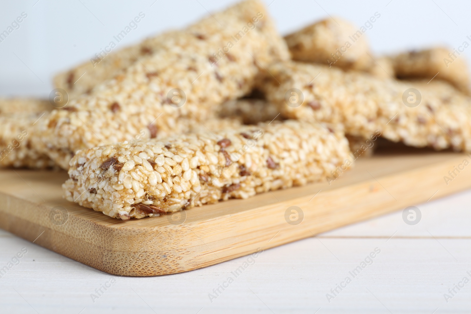 Photo of Tasty sesame seed bars on white wooden table, closeup