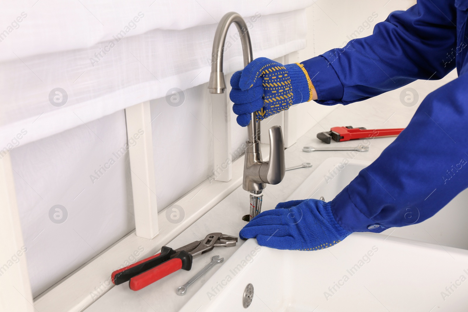 Photo of Plumber repairing water tap in kitchen, closeup