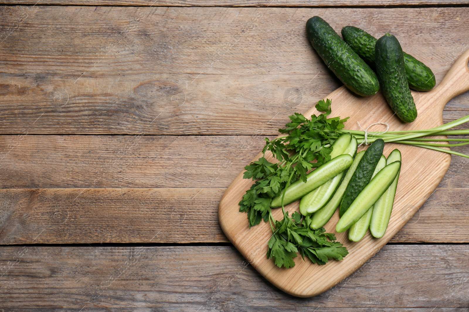 Photo of Fresh ripe cucumbers and parsley on wooden table, flat lay. Space for text