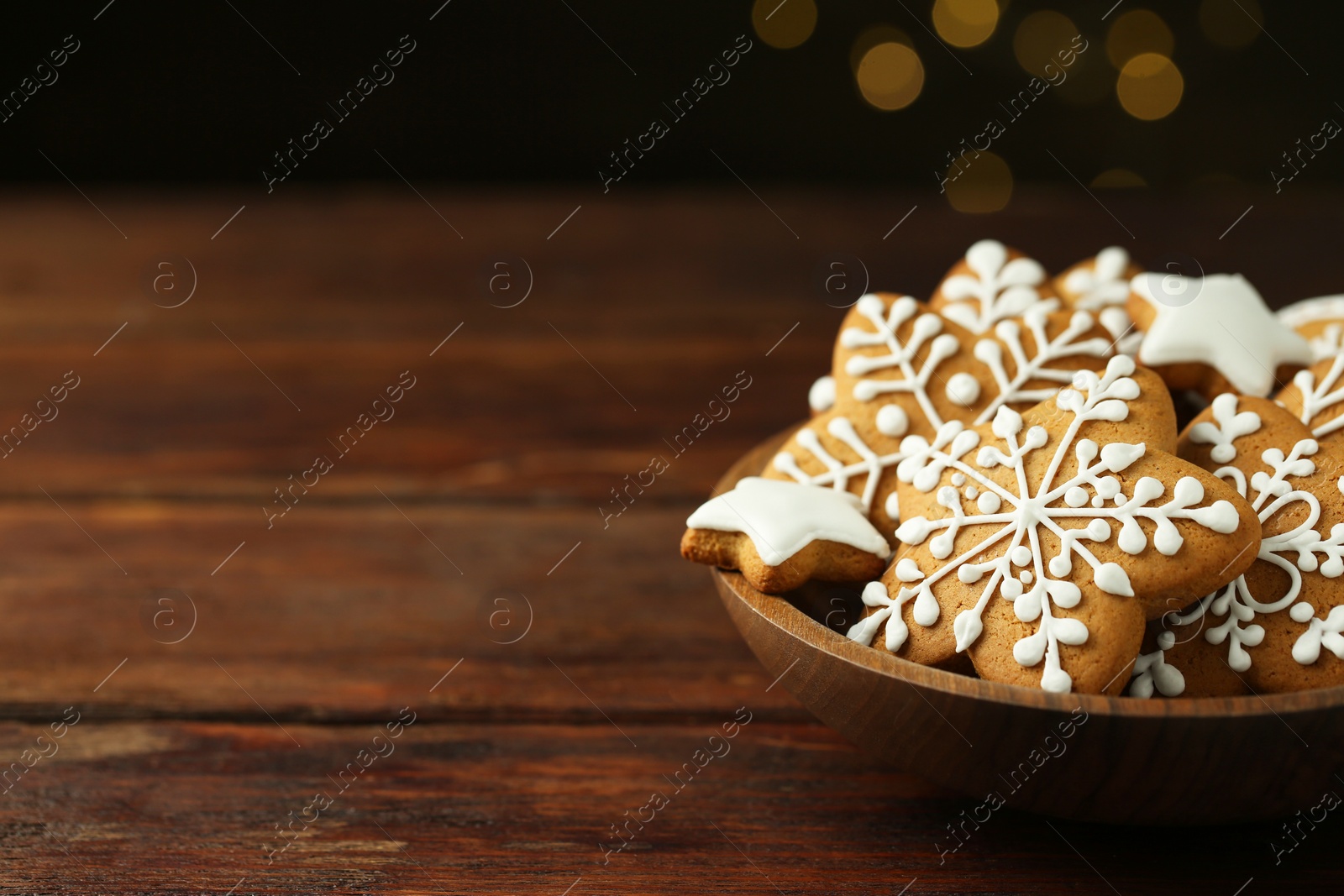 Photo of Tasty Christmas cookies with icing on wooden table. Space for text