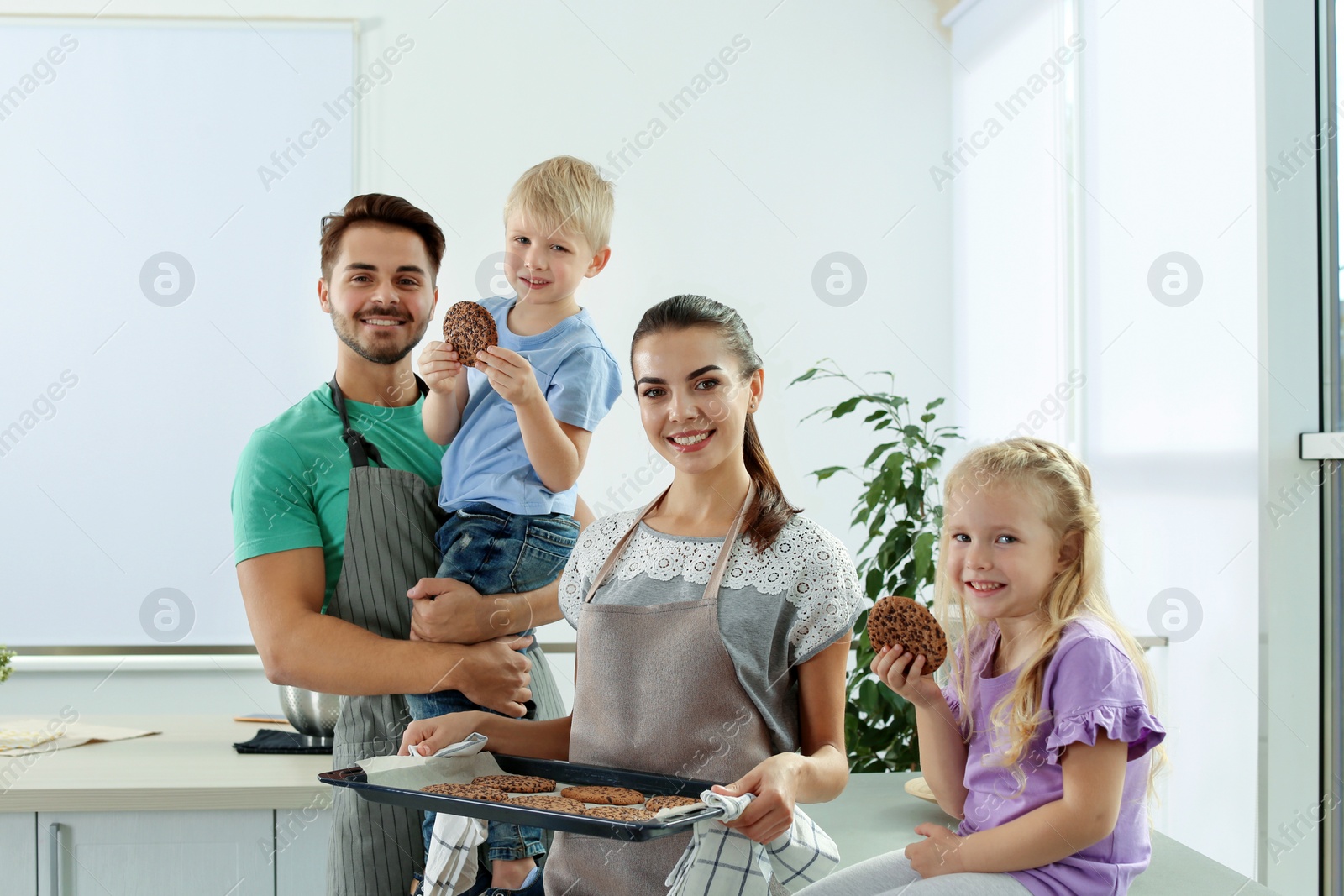Photo of Happy family with homemade oven baked cookies in kitchen