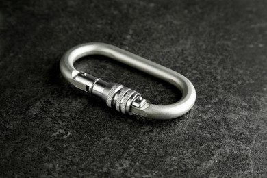 Photo of One metal carabiner on black table. Safety equipment