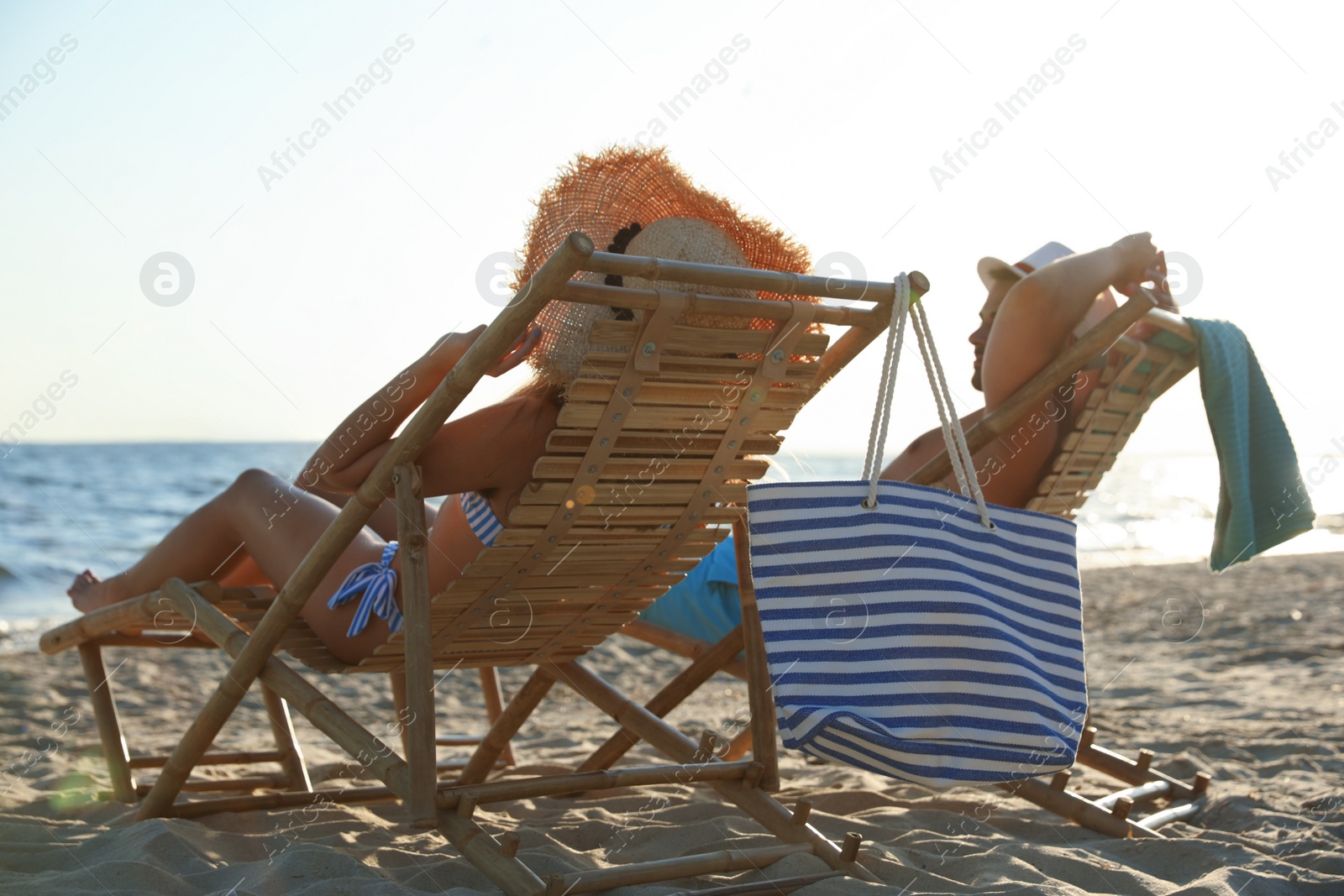 Photo of Young couple relaxing in deck chairs on beach near sea