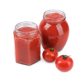 Photo of Organic ketchup in glass jars and fresh tomatoes isolated on white. Tomato sauce