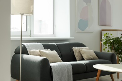 Photo of Gray couch with pillows, white coffee table and lamp in living room