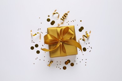 Beautiful golden gift box and confetti on white background, flat lay