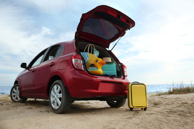 Photo of Red car with luggage on beach. Summer vacation trip