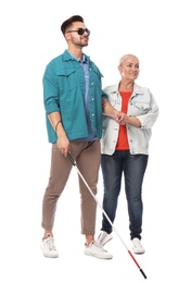 Photo of Mature woman helping blind person with long cane on white background