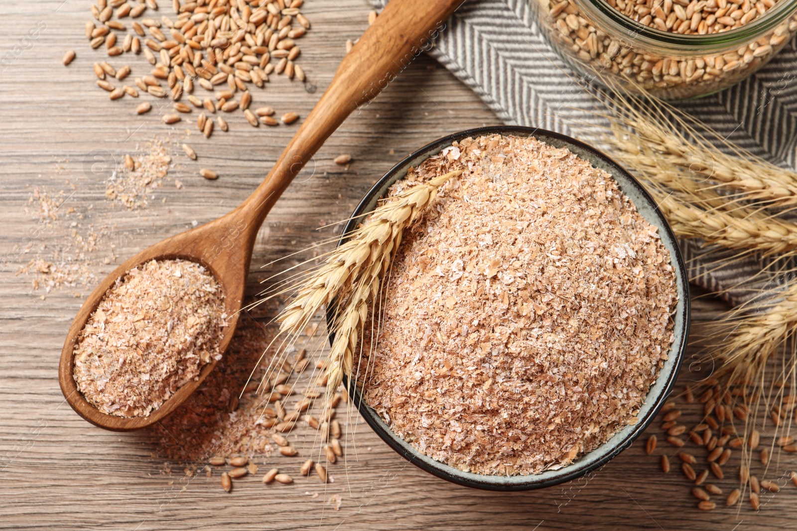 Photo of Wheat bran, kernels and spikelets on wooden table, flat lay