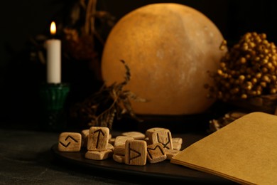 Photo of Composition with wooden runes and old book on black table