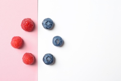 Flat lay composition with raspberries and blueberries on color background