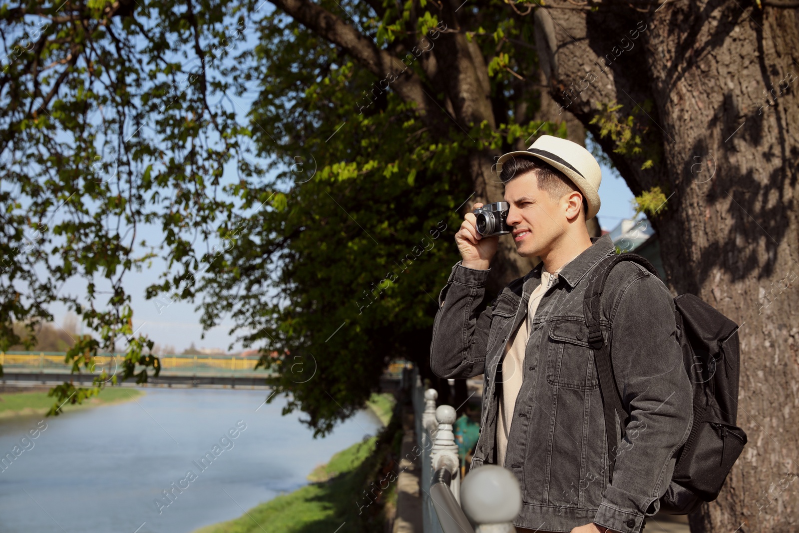 Photo of Tourist taking picture on city street near beautiful river