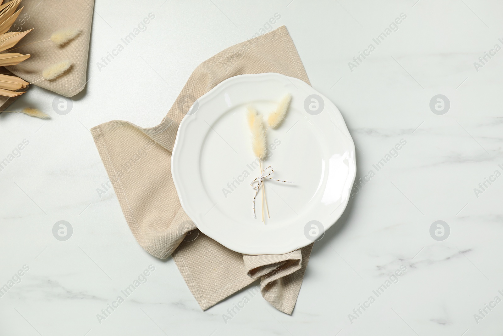 Photo of Elegant plate with spikes and napkin on white marble table, top view