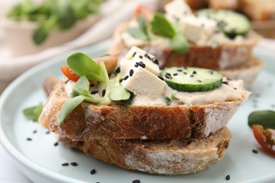 Tasty vegan sandwiches with tofu, cucumber, tomato and sesame seeds on table, closeup