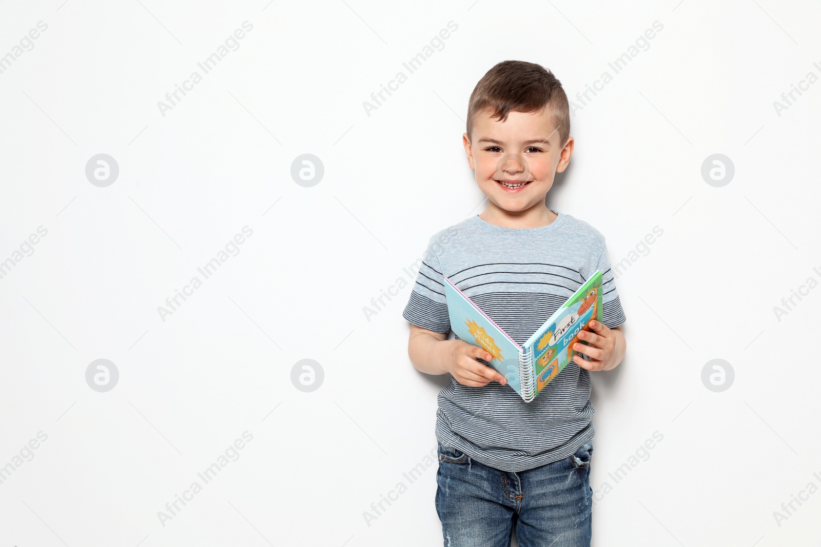 Photo of Cute little boy reading book on white background, space for text