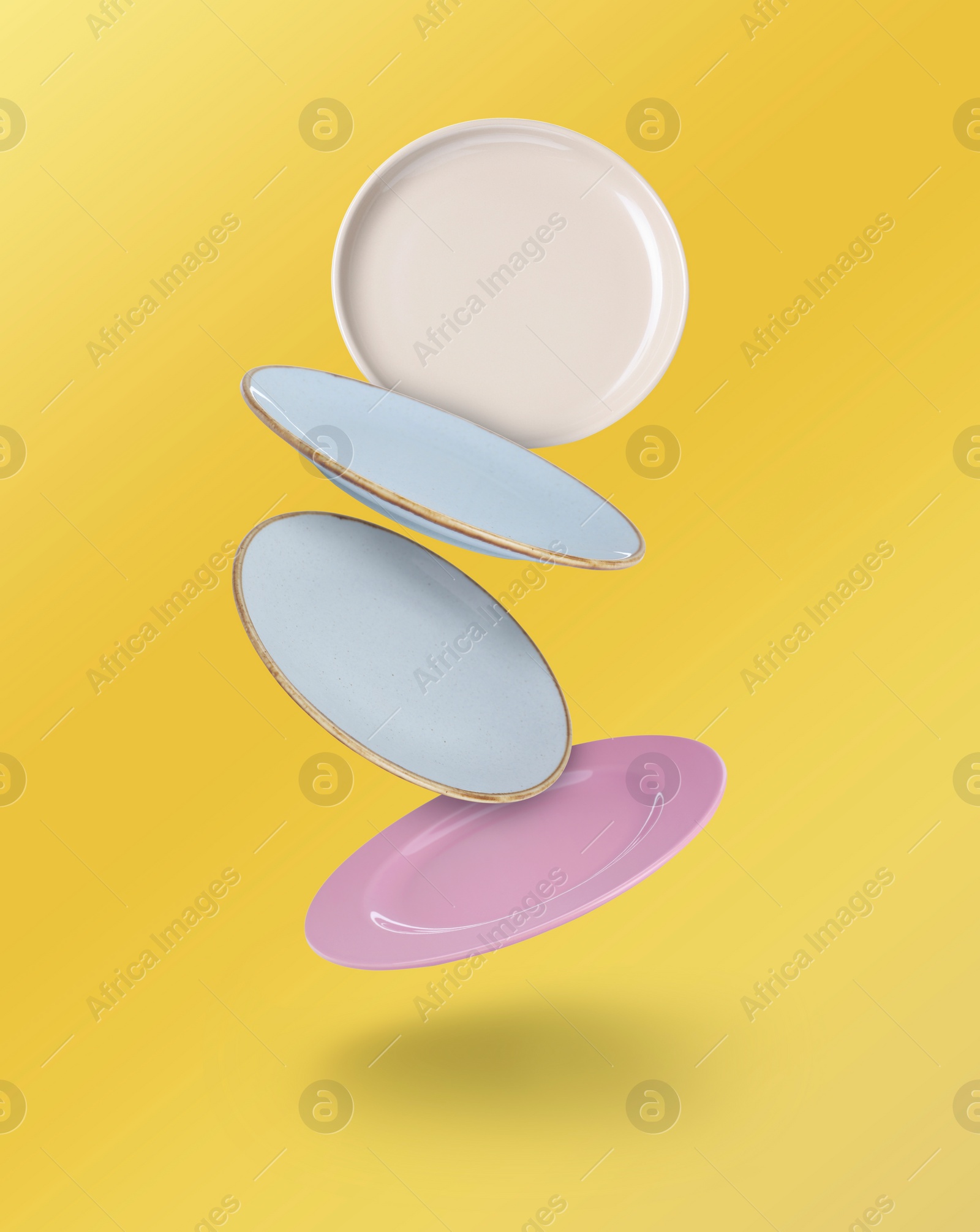 Image of Many different plates falling on yellow gradient background