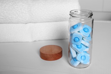 Photo of Glass jar with water softener tablets on washing machine in bathroom, space for text