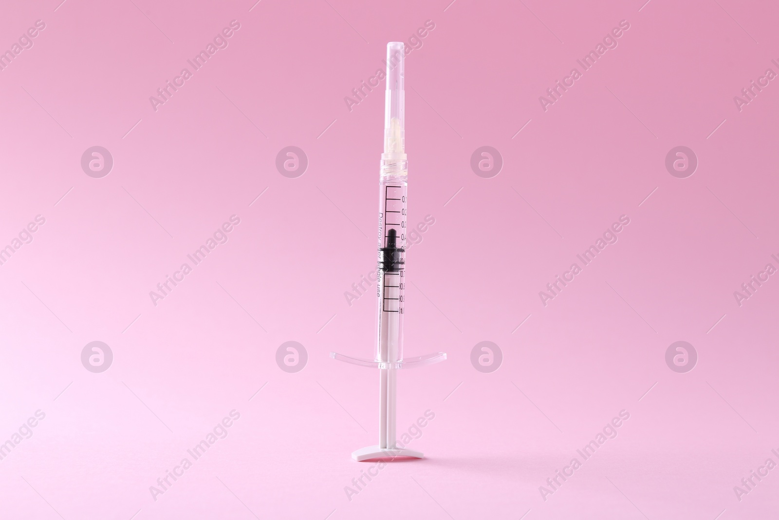 Photo of Cosmetology. One medical syringe on pink background