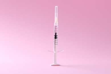 Cosmetology. One medical syringe on pink background