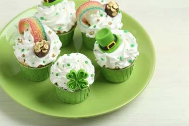 Photo of St. Patrick's day party. Tasty festively decorated cupcakes on white table, closeup. Space for text