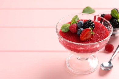 Photo of Delicious panna cotta with fruit coulis and fresh berries served on pink wooden table. Space for text