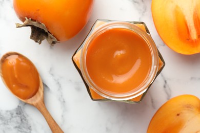 Photo of Delicious persimmon jam and fresh fruits on white marble table, flat lay