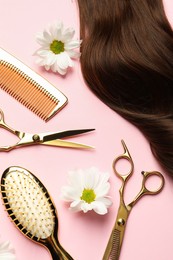 Flat lay composition with different hairdresser tools and flowers on pink background